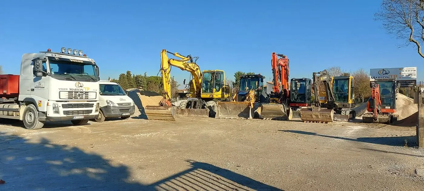 Le parc matériel de Marson TP aligné sur le dépôt : camions bennes et pelles mécaniques